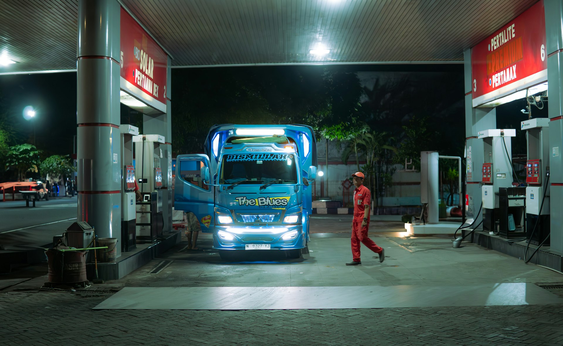 A man in a red jumpsuit walking towards a blue truck